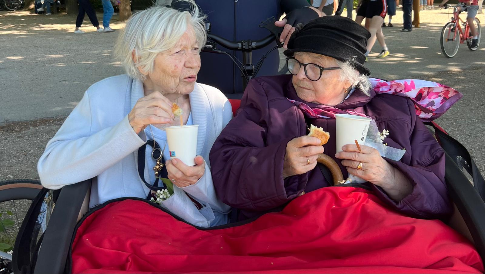 2 personnes âgées dans un triporteur qui boivent un chocolat chaud