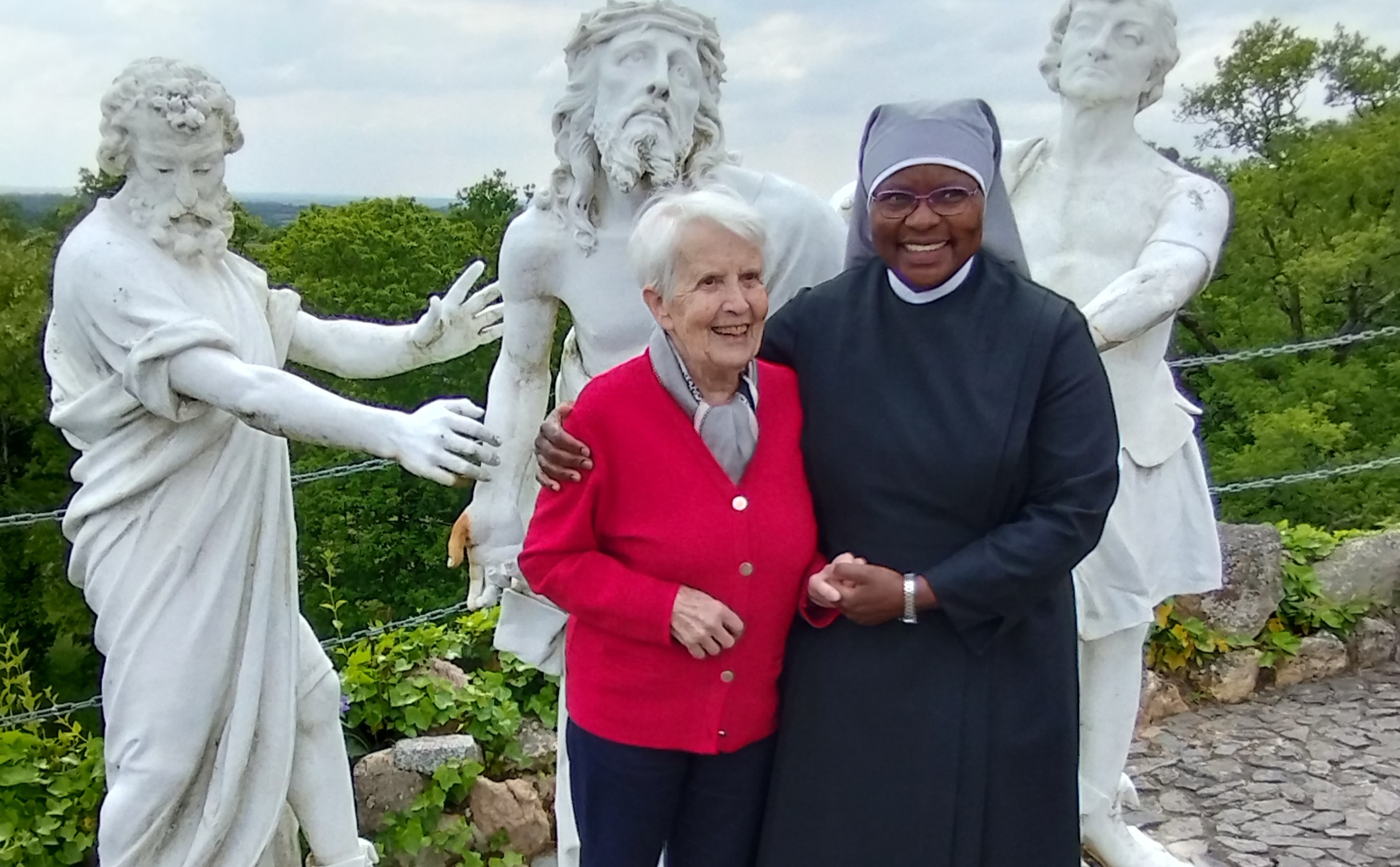 1 personne âgée et une petite sœurs devant des statues