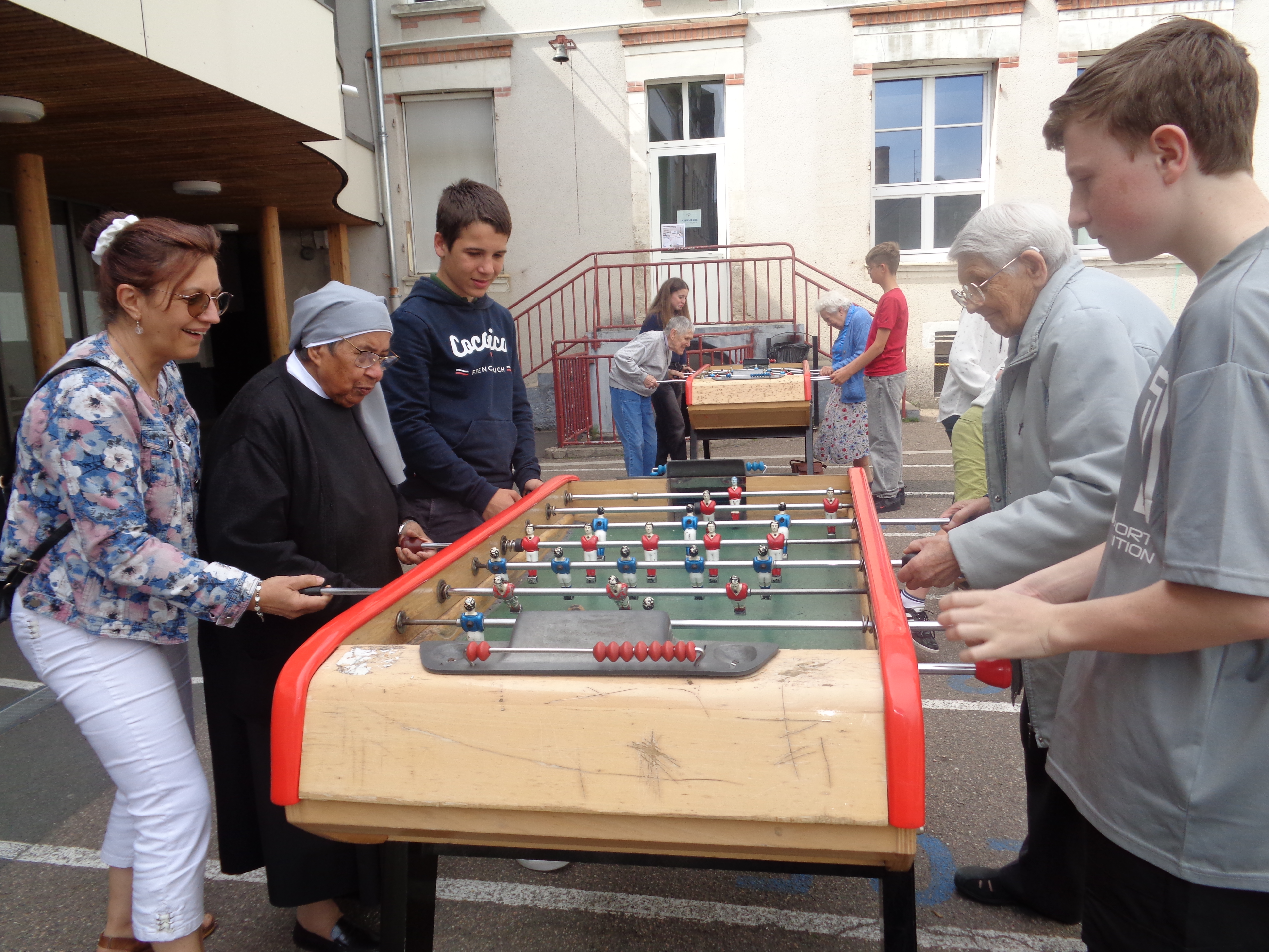 Personnes âgées et ados qui jouent au babyfoot