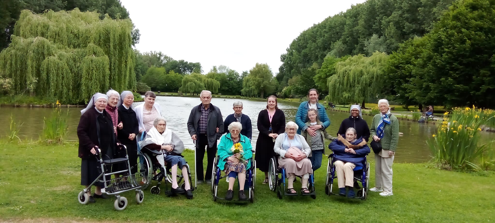 Personnes âges et petite sœurs dans un parc au bord d'un étang