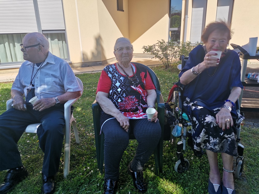 3 personnes âgées qui boivent un verre assise dans le jardin