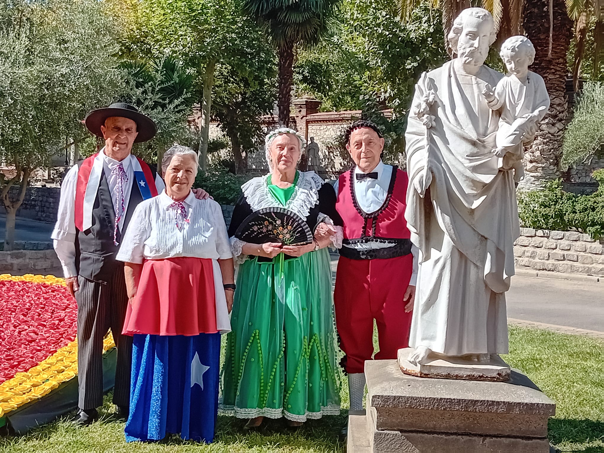 Personnes âgées en costumes espagnol devant une statue de Saint Joseph