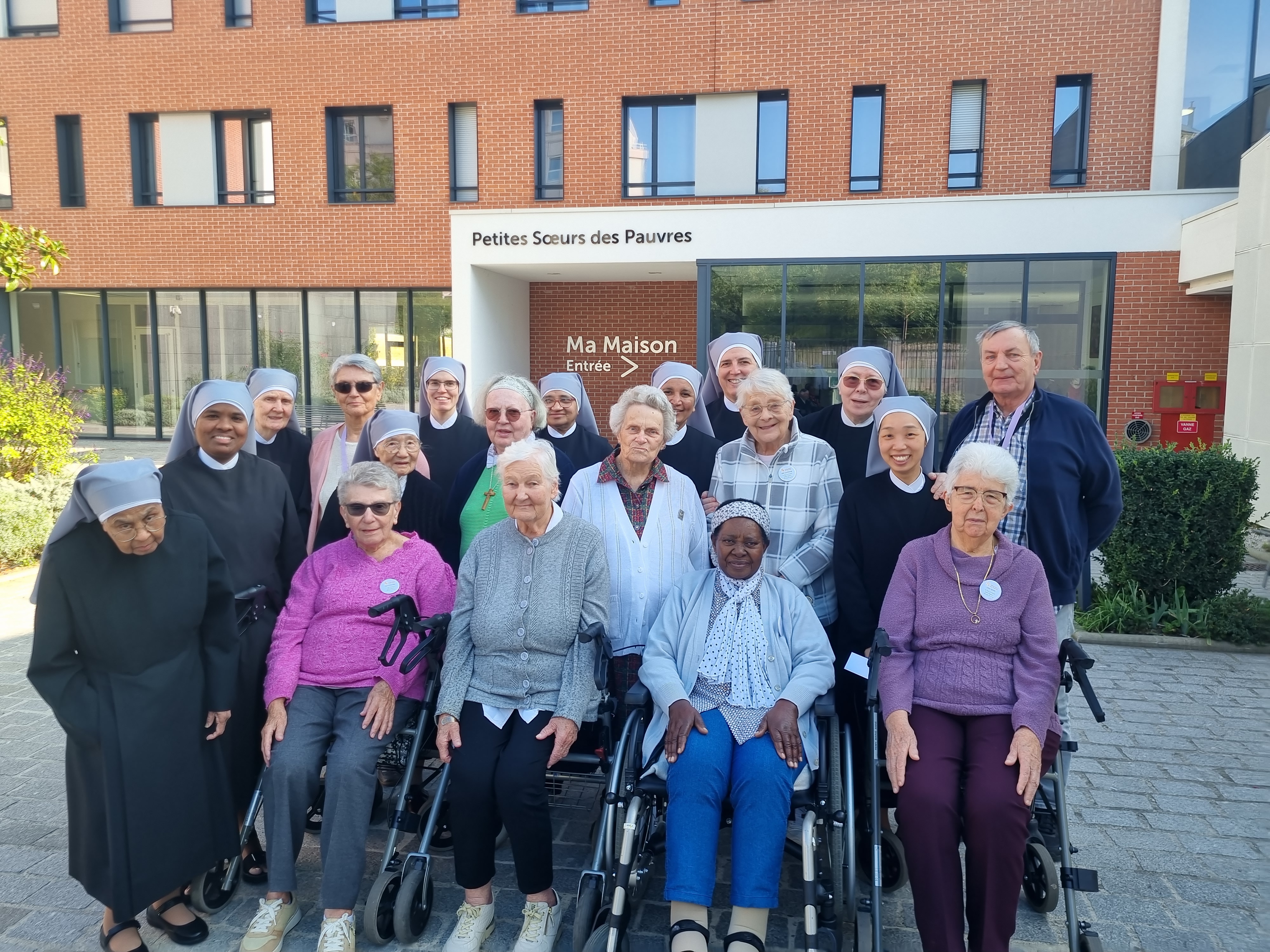 Personnes âgées et petites sœurs devant une maison des petites sœurs des Pauvres