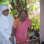Petite soeur aidant une personne âgée à marcher, en Inde