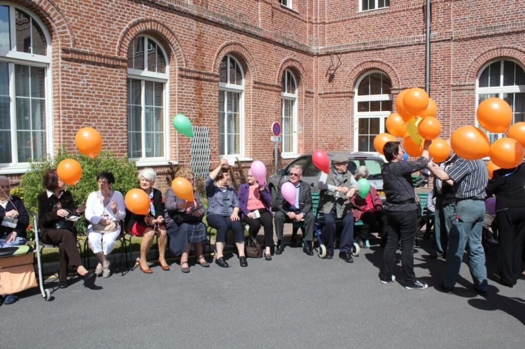 personnes âgées devant la maison avec des ballons dans les mains