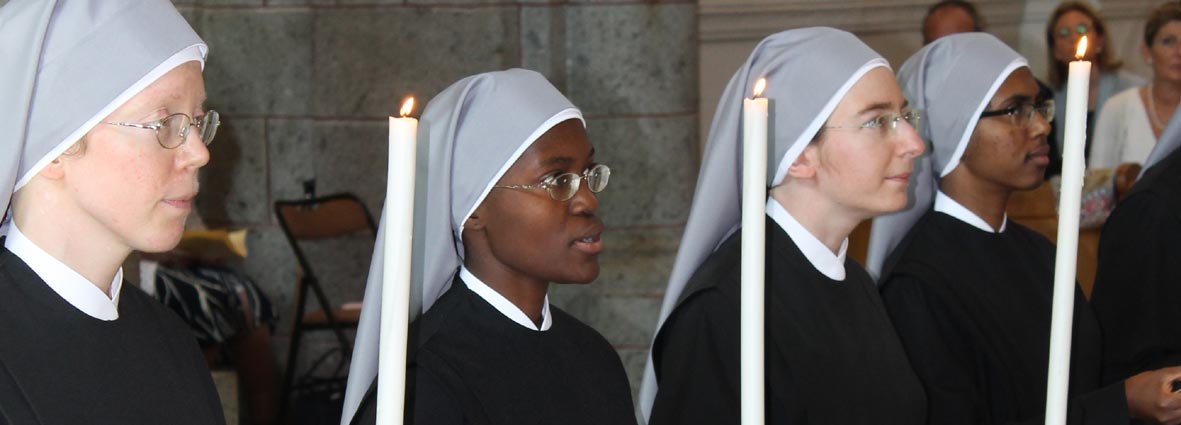visages de Petites soeurs avec cierges lors de leurs voeux perpétuels
