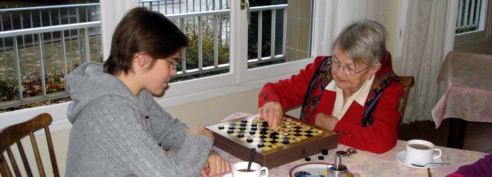 jeune fille et personne âgée jouant au jeu de dames