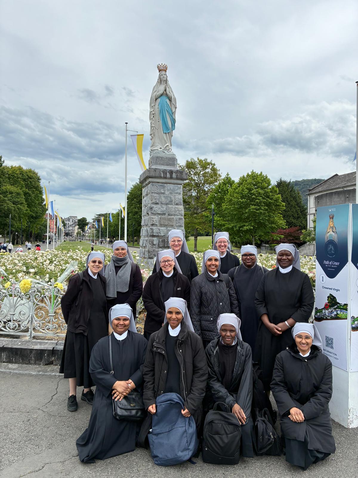 Rencontre de petites sœurs des pauvres à Lourdes devant une statue de Notre dame