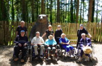 Personnes âgées au zoo devant une statue d'ours avec des petites sœurs des pauvres au soleil